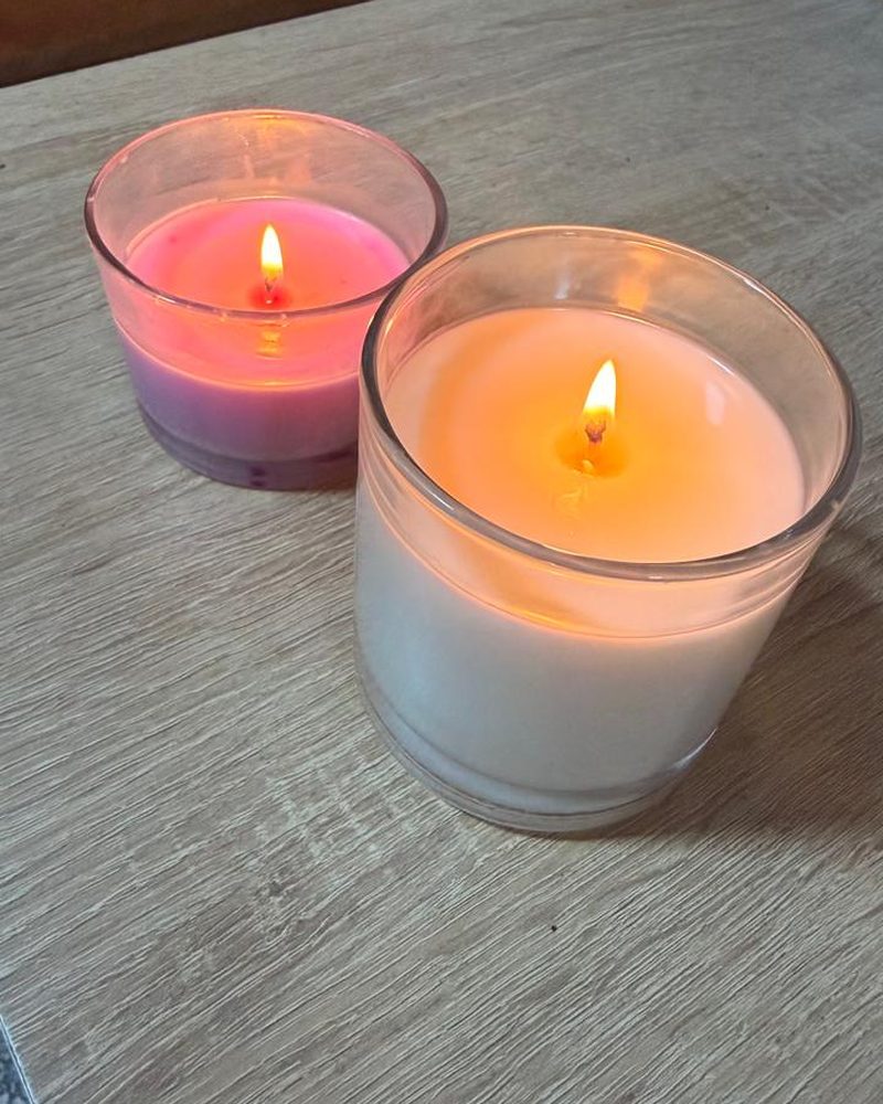 Deux bougies allumées en verre transparent posées sur une table en bois